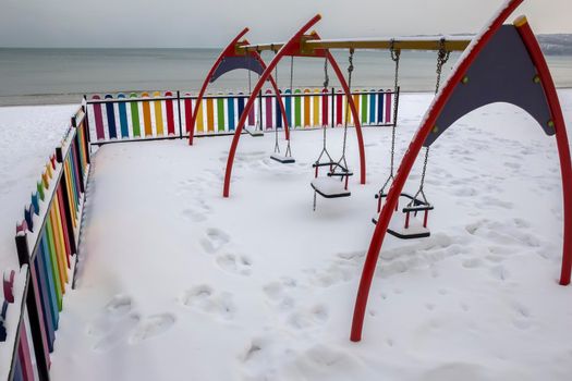 View of colorful children's swings covered with snow during winter