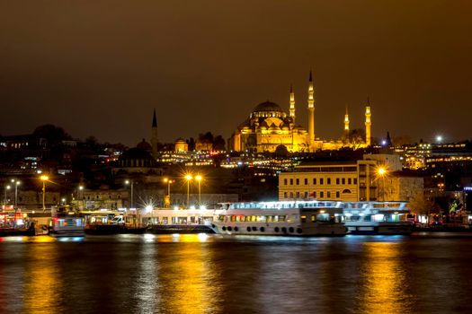 Illuminated Istanbul at night. Turkey. Night view of historical part of Sultanahmet area Famous mosques, pier with boats, cafes, bars and shops. Bosphorus river with boats.