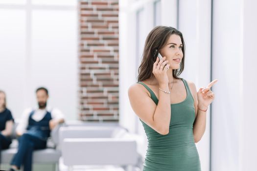 young woman talking on a smartphone standing in the office.photo with copy space