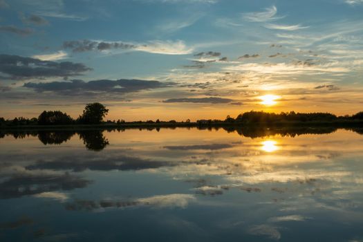 Mirror reflection of clouds in the calm lake water during sunset