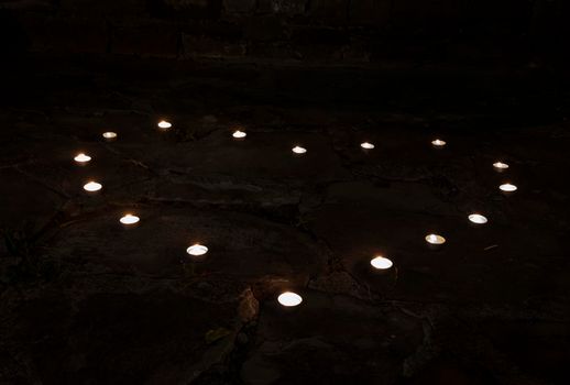 burning tea candles shaped like a heart in the darkness
