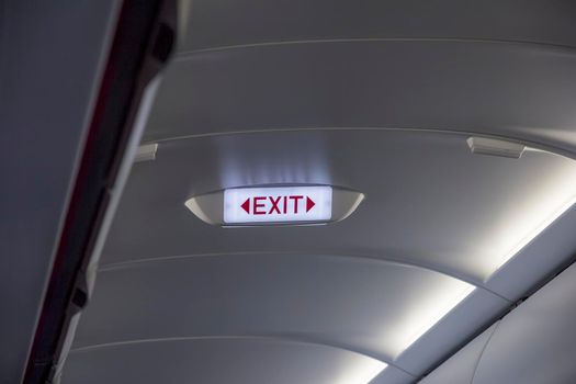 emergency exit sign on the ceiling of airplane 