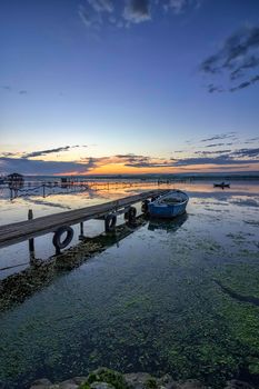 exciting twilight on a shore with pier and boat. Vertical view