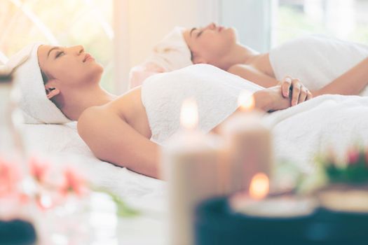 Relaxed young woman lying on spa bed prepared for facial treatment and massage in luxury spa resort. Wellness, stress relief and rejuvenation concept.