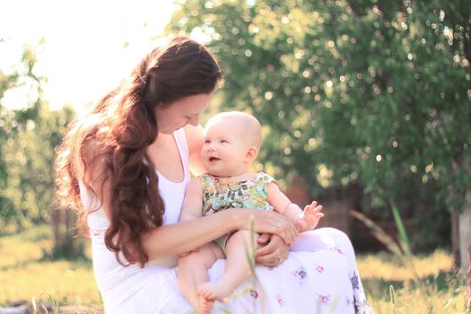 mom talking to the baby sitting on a bench in the Park.