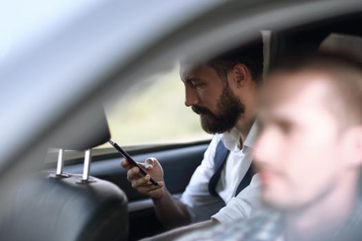 close up.businessman reading SMS on his smartphone, sitting in the car. people and technology