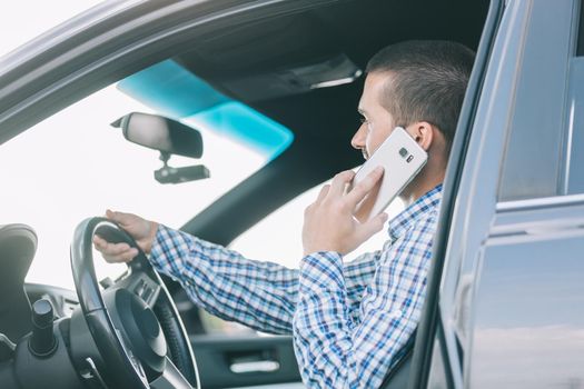 close up.modern man talking on a smartphone, sitting behind the wheel of a car.