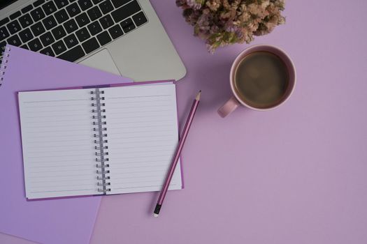 Flat lay laptop computer, notebook and coffee cup on purple background.