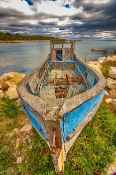 An abandoned old wooden fishing boat on the beach with amazing sky