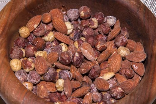 Lots of roasted almonds, hazelnuts in wooden bowl. Close