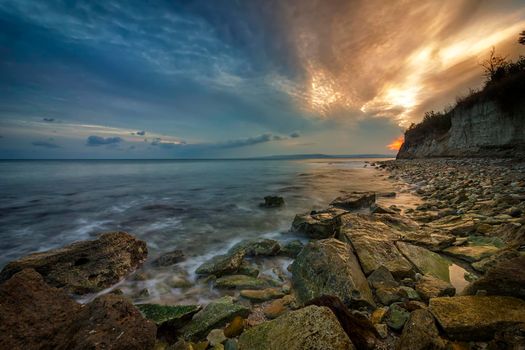Beauty sea rocky coast with slow shutter and waves flowing out.