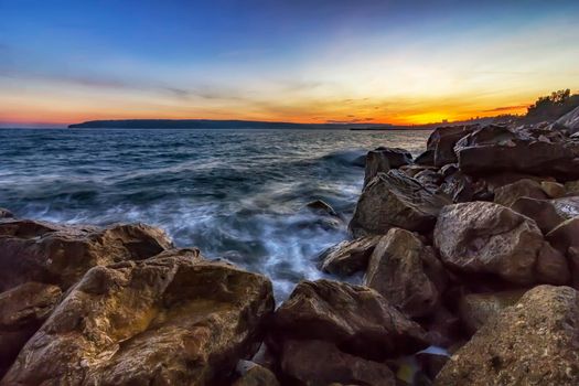 Sunset over the sea . Big rocks in the foreground