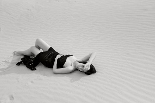 girl in a black long dress in a sandy desert under a blue sky