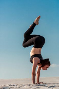 Side view of concentrated fit brunette performing leg and glute workout, doing squats in studio on grey background. Fitness concept