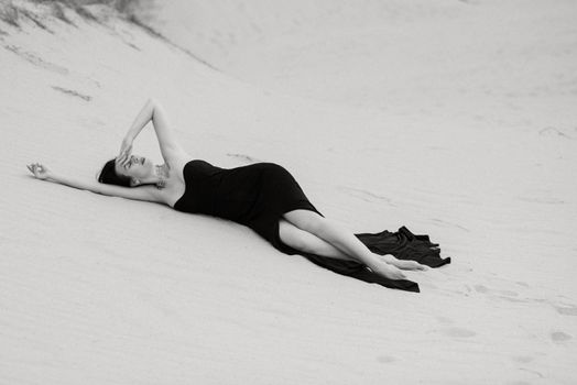 girl in a black long dress in a sandy desert under a blue sky