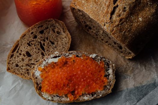 Putting red caviar on bread and butter, close-up of caviar sandwich. Salmon salted orange roe. Raw seafood. Luxury gourmet food. Delicious and tasty fish products. Russian cuisine