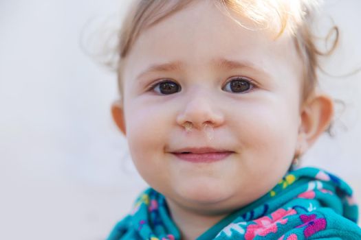 Baby plays snot in the street with a cold nose. Selective focus. Child.