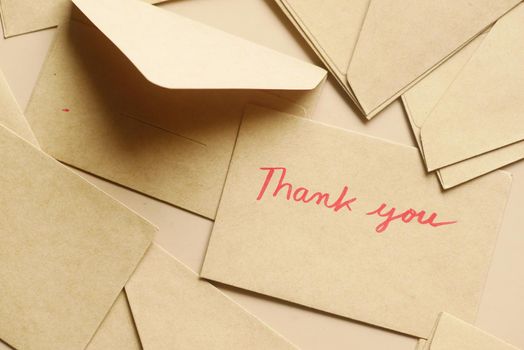 thank you message and envelope on wooden table.