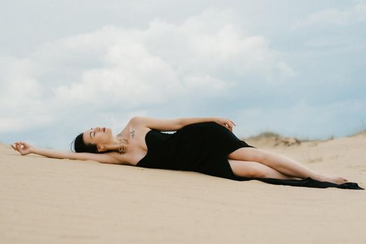 girl in a black long dress in a sandy desert under a blue sky