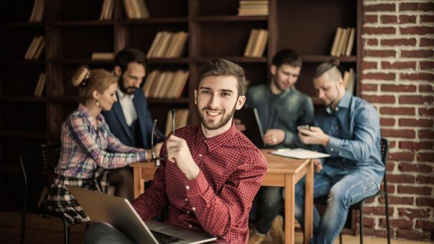 in the foreground the successful employee of the company with laptop on the background of business team