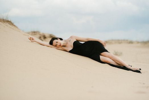 girl in a black long dress in a sandy desert under a blue sky