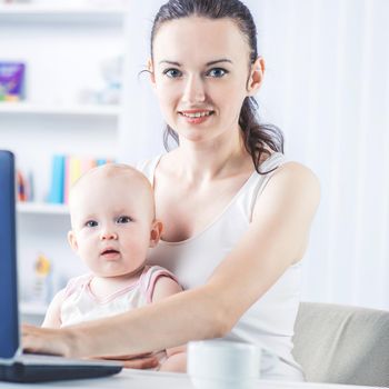 young mother and baby using laptop to communicate with grandma via Skype,at home in the nursery