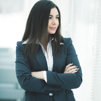 closeup of successful business woman standing near window with hands clasped in front of him .the photo has a empty space for your text