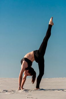 Side view of concentrated fit brunette performing leg and glute workout, doing squats in studio on grey background. Fitness concept