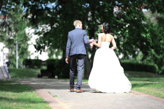 rear view.the happy couple walk through the Park. the day of the wedding.