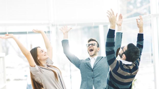 jubilant business team standing in a circle, hands up in rejoice success.the photo has a empty space for your text.