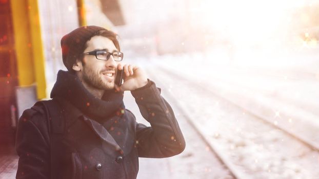 stylish young man talking on the smartphone is at the metro station