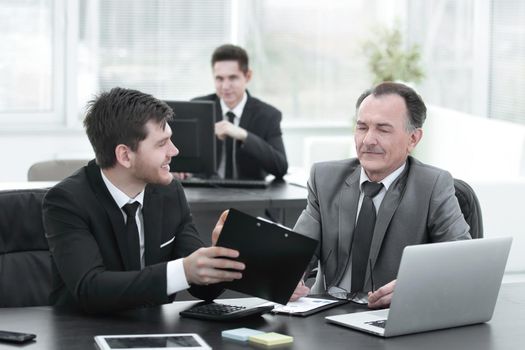 boss and employee discussing the document sitting at the Desk in the office.photo with copy space
