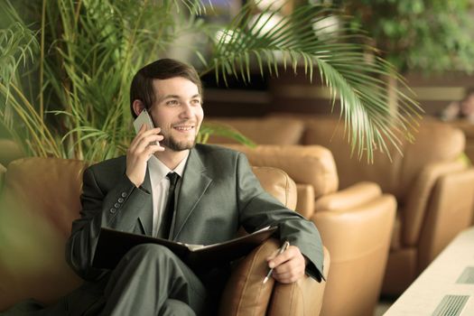 businessman with business papers talking on the smartphone sitting in a chair the modern office