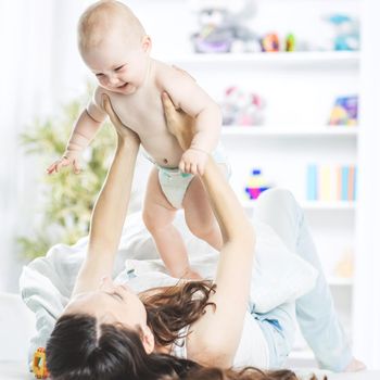 happy mother playing with baby on bed in child's room child's room