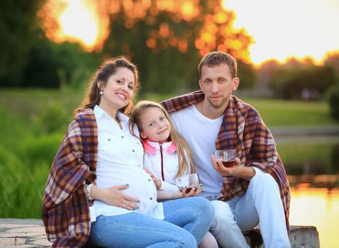 happy family wrapped in a blanket drinking hot tea sitting on a bench in the cool autumn day .the photo has a space for your text