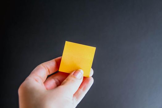 Hand with colorful notes on black background