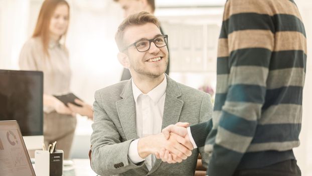 handshake colleagues from the business team near the workplace in the modern office.
