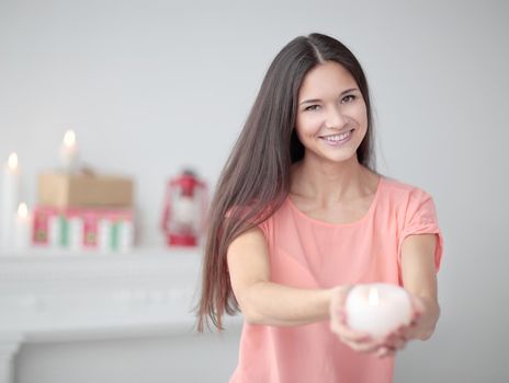 close up.a pretty young woman stretches a burning candle.