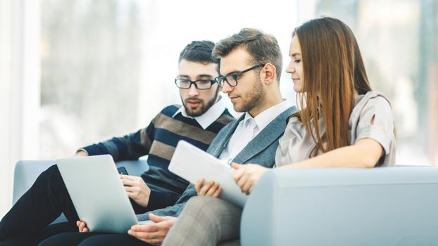 employees with a laptop sitting in the lobby of the office.the photo has a empty space for your text.