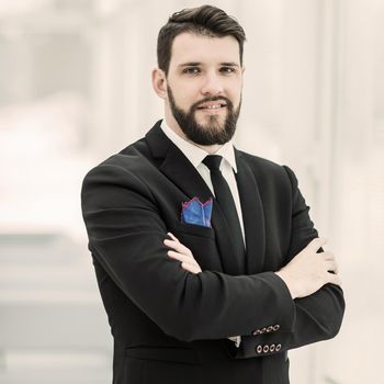 portrait of successful businessman standing near a window in bright office.the photo has a empty space for your text