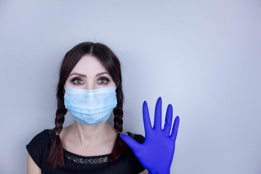 Woman wearing protection face mask against coronavirus. Woman in a mask looking shocked or worried with hand up. Medical mask, medical gloves, Close up shot, Select focus, Prevention from covid19