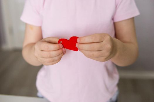 A blogger girl makes a felt craft for Valentine's Day in the shape of a heart. The concept of children's creativity and handmade.