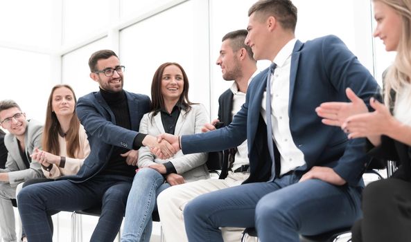 group of employees congratulating their colleague at a work meeting