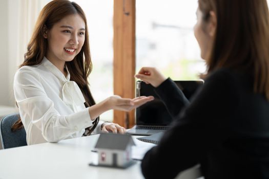 real estate agent holding house key to his client after signing contract agreement in office,concept for real estate, moving home or renting property.