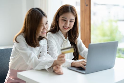Two asian girlfriends shopping online with smart phone and credit card at home