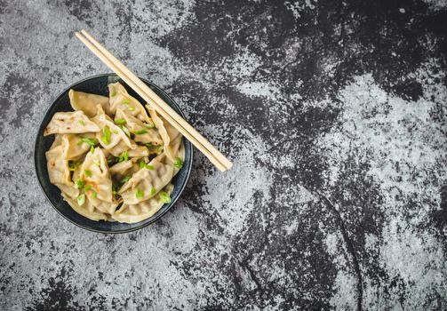 Asian dumplings in bowl, chopsticks, rustic stone background. Top view. Space for text. Chinese dumplings for dinner. Closeup. Copy space. Traditional Asian/Chinese cuisine. Overhead. Dim sum