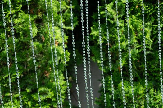 Decoration with transparent beads on a background of blurred greenery.