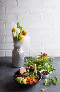 Table with fresh clean organic food. Quinoa vegetables salad bowl, salad leaves, flowers bouquet. Superfood or detox eating concept. Spring setting. Vegan/vegetarian food. Make salad. Space for text