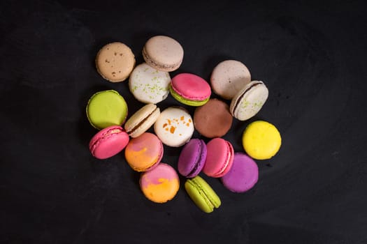 Assorted colorful french cookies macarons on a dark background. Closeup. Concept of the macarons