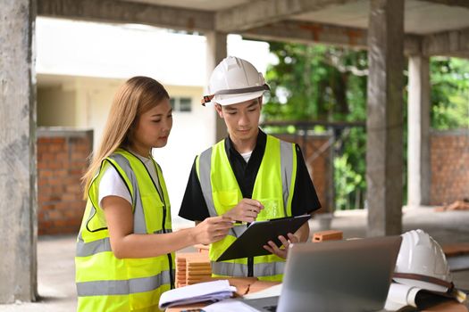 Focused architects discussing with engineer about their project at construction site.